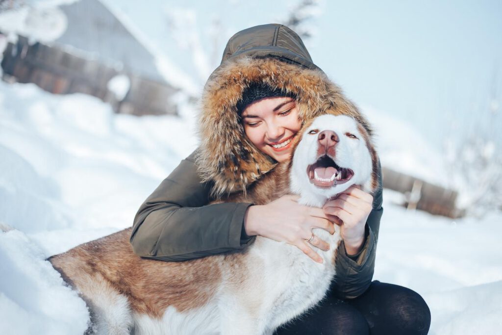 woman hugging her dog in the snow sloped roof petroleum jelly large dogs several publications house keep dogs warm fresh water
