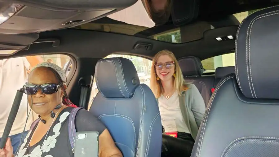 image of a couple of visually impaired people sitting in the waymo autonomous self driving vehilce for scoop master pet waste removal service blog post.